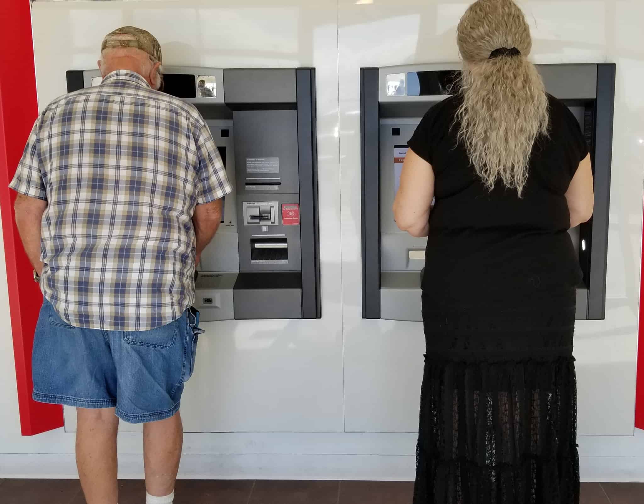 man and woman consult ATMs separately to find out the bank balance