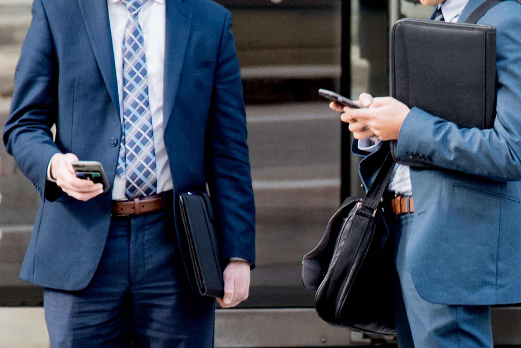 two men in suits using their cell phone