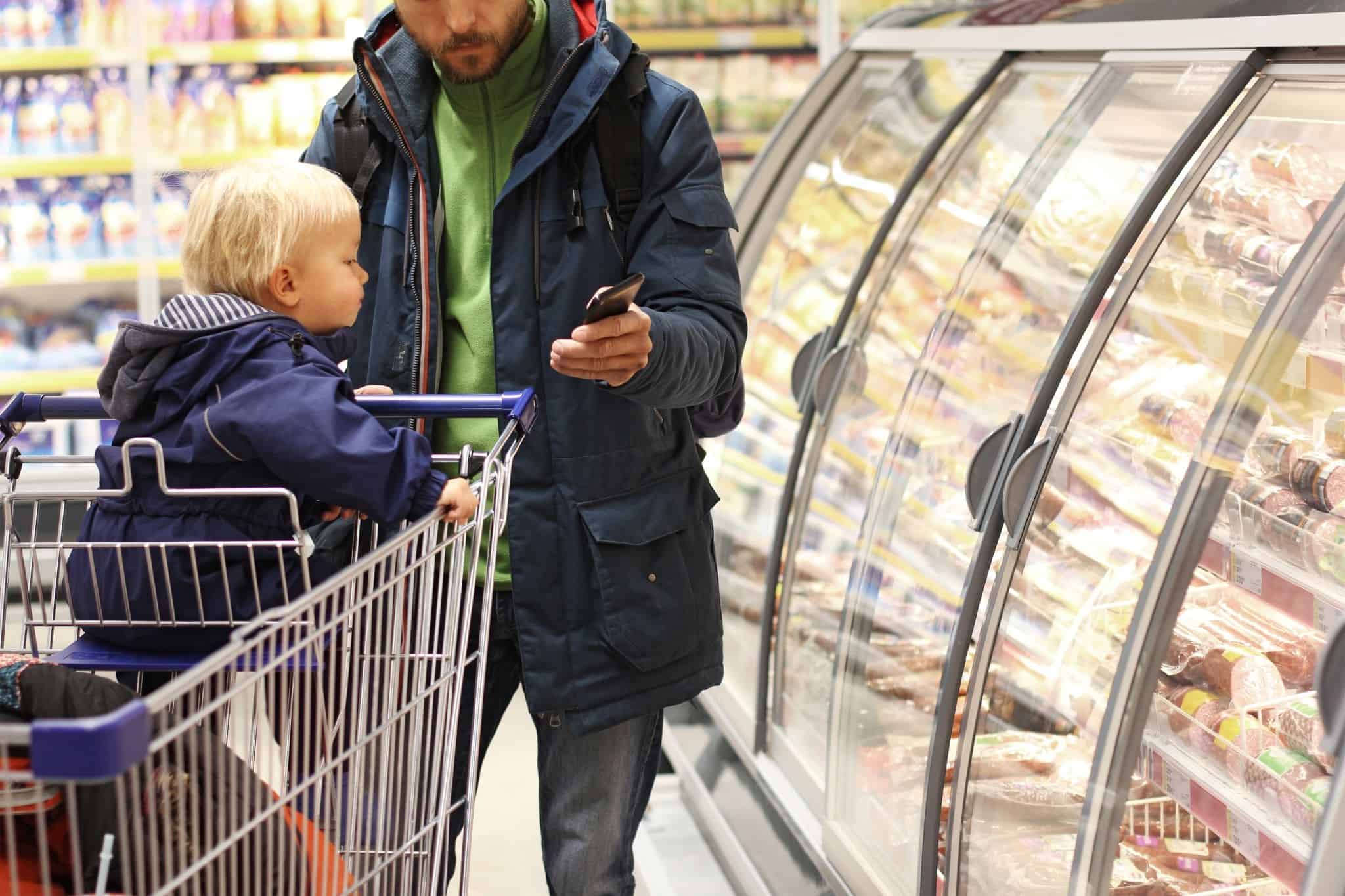 Man with child at the supermarket does the math on rising prices