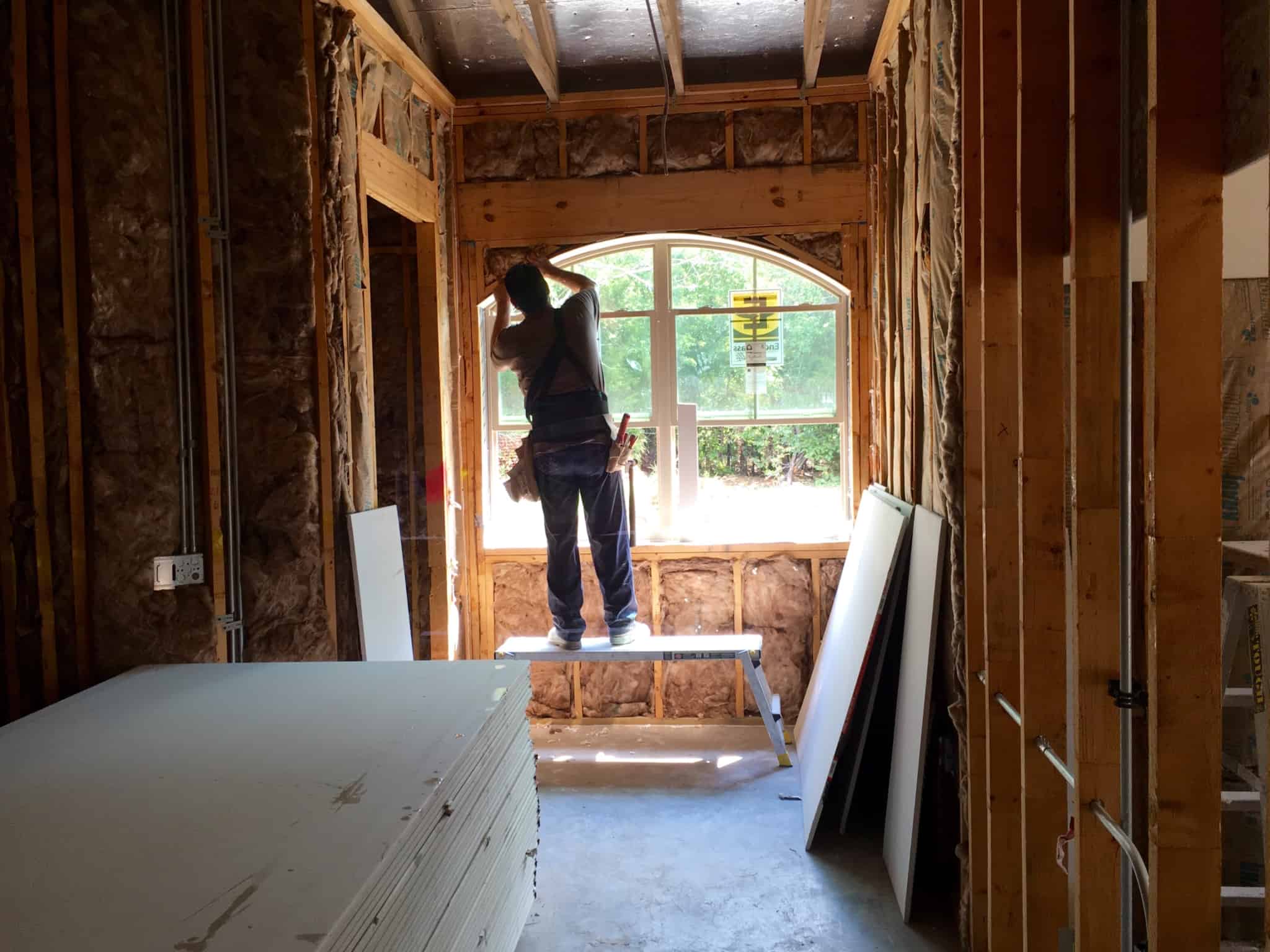 man building the interior of a house, works by a window