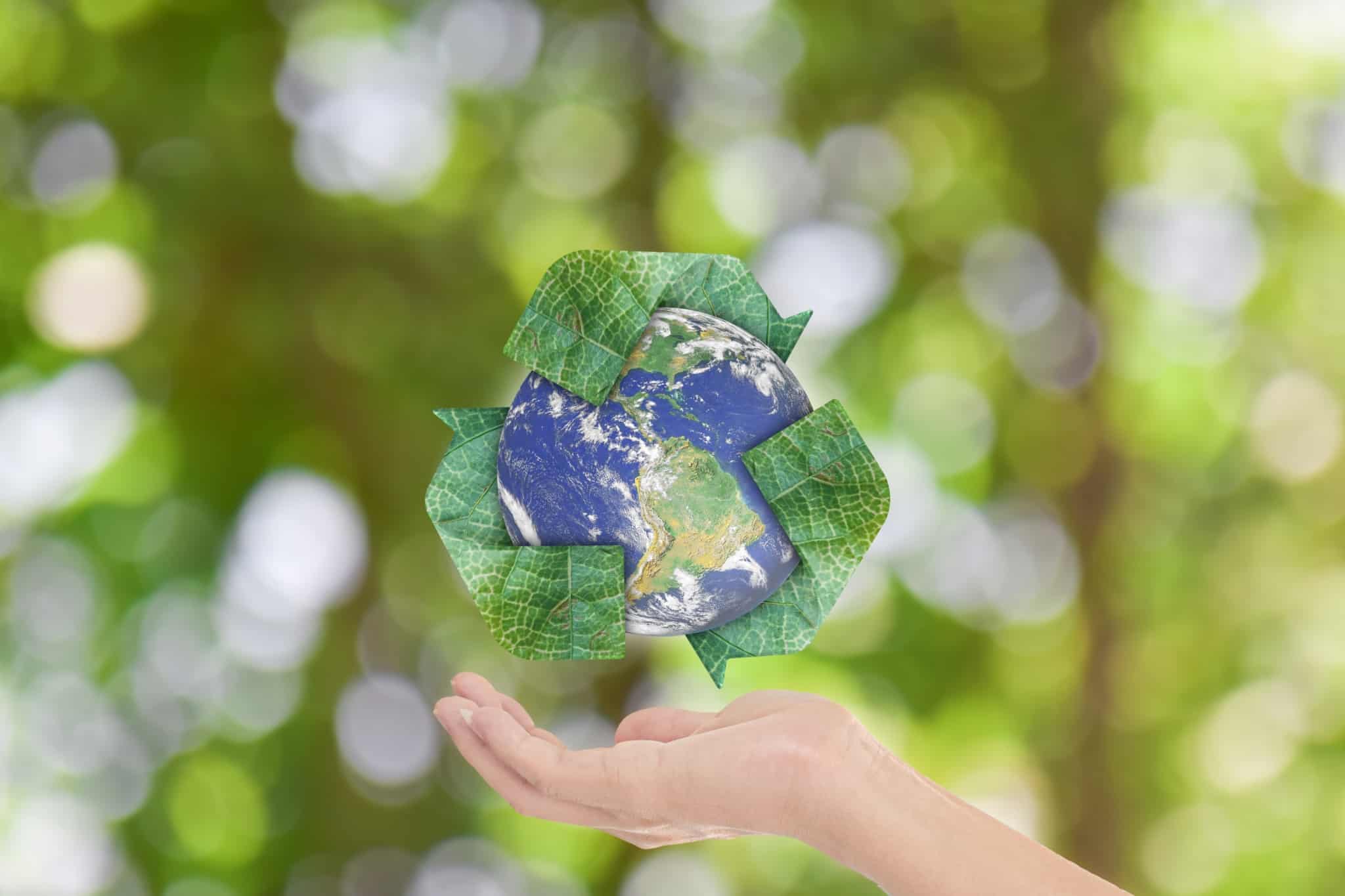 the world with the green recycling symbol around it and a hand underneath it as if to hold it