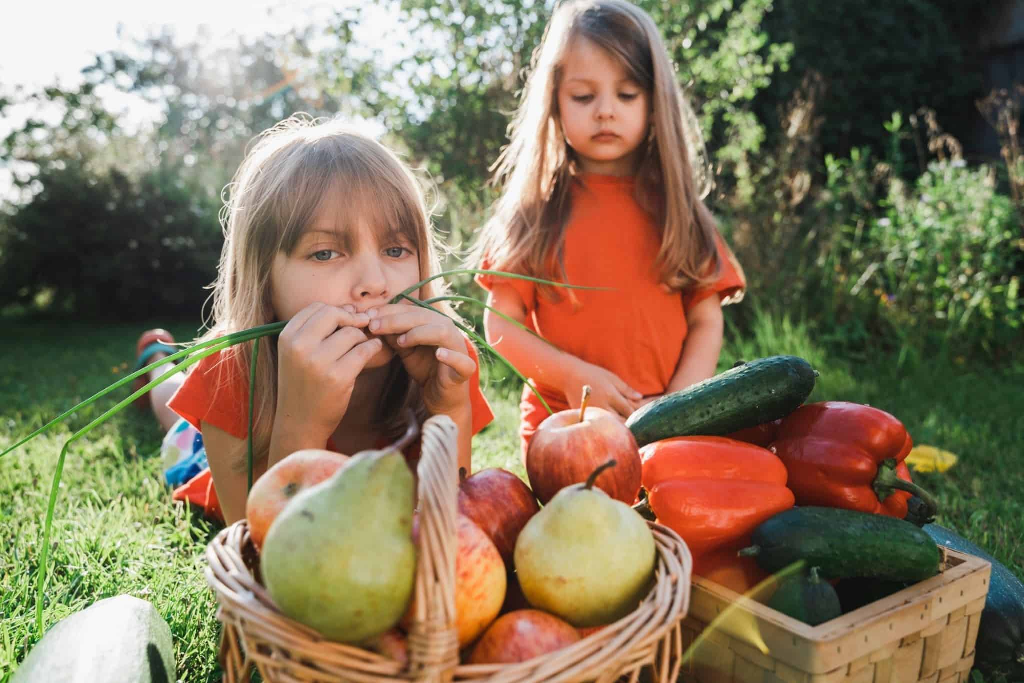 Children in front of fruit and vegetable baskets evoking food waste
