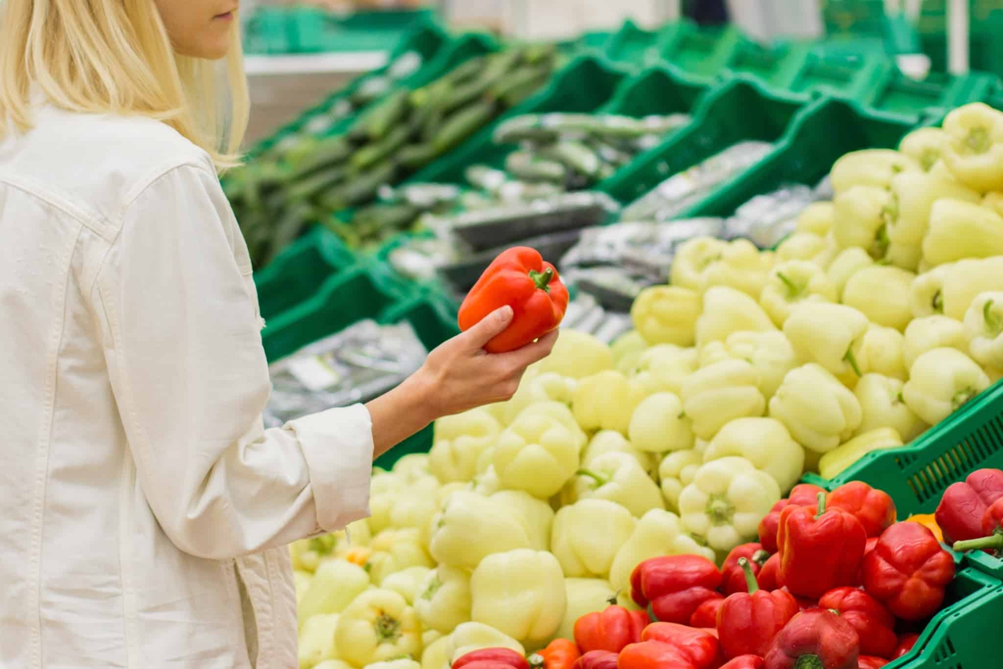 young woman shopping at the supermarket, choosing the freshest vegetables, part of her vegetarian diet
