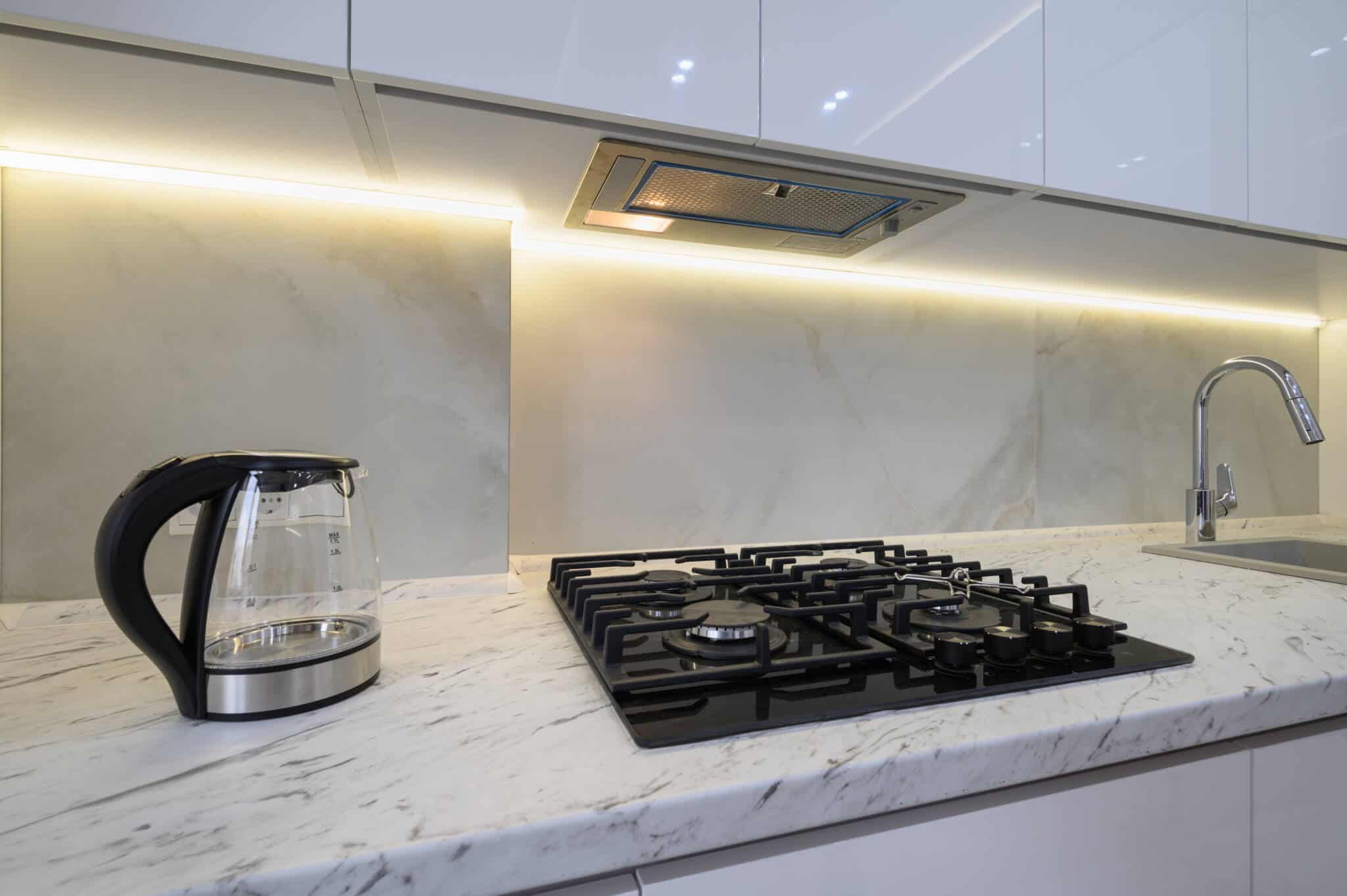 gas and electricity and the possibility of returning to the regulated market illustrated with a modern white kitchen worktop with a gas stove and strong lighting on the upper unit