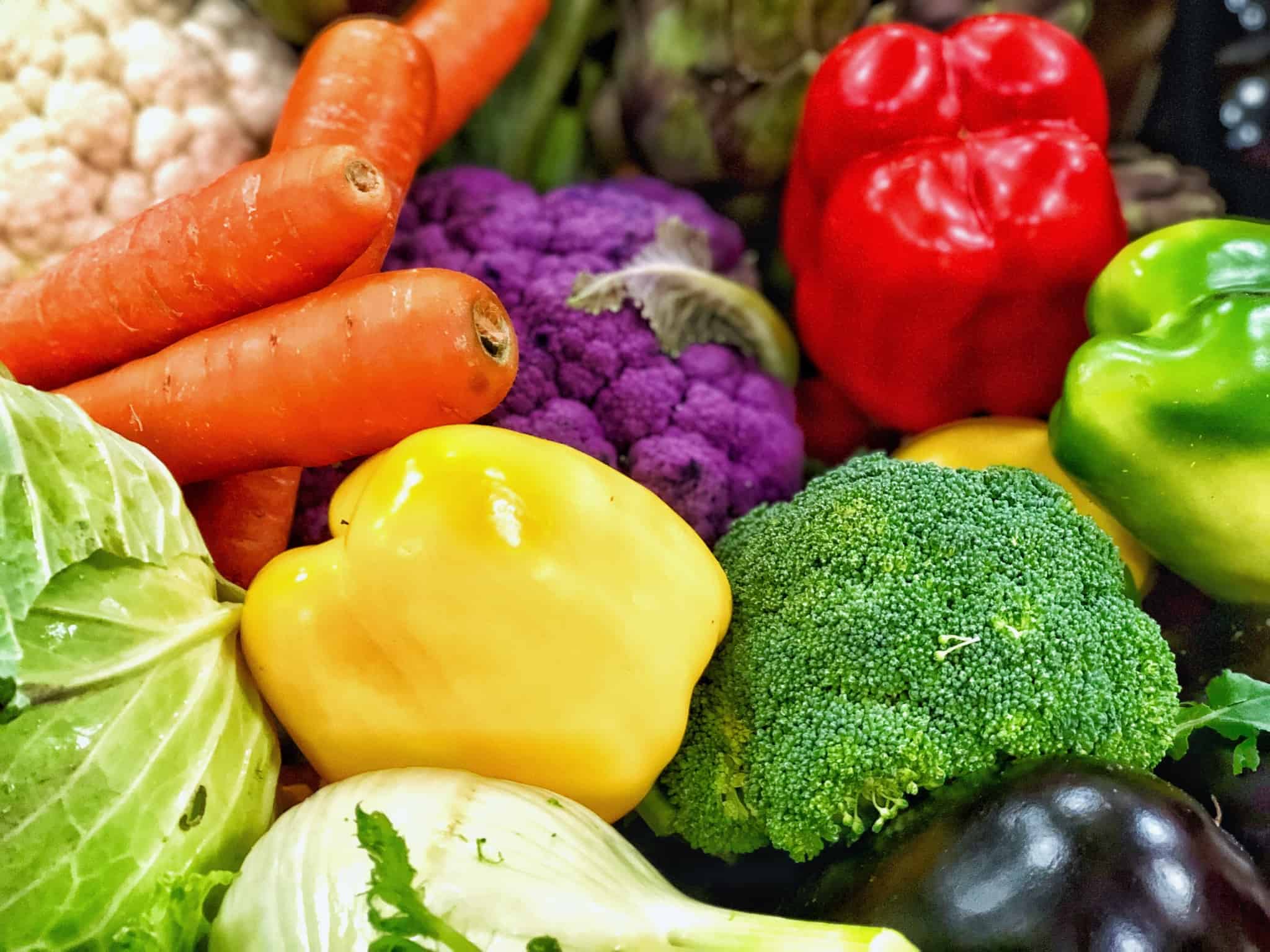 Various vegetables arranged such as carrots, peppers, broccoli, kale